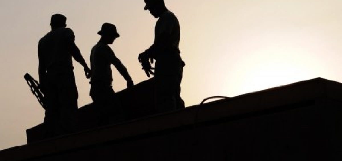 Three construction site workers wearing hardhats in the sun