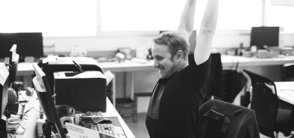 happy worker stretching at his desk