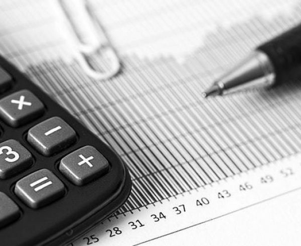 Closeup of a calculator and pen placed on top of a report as SAF refunds are calculated