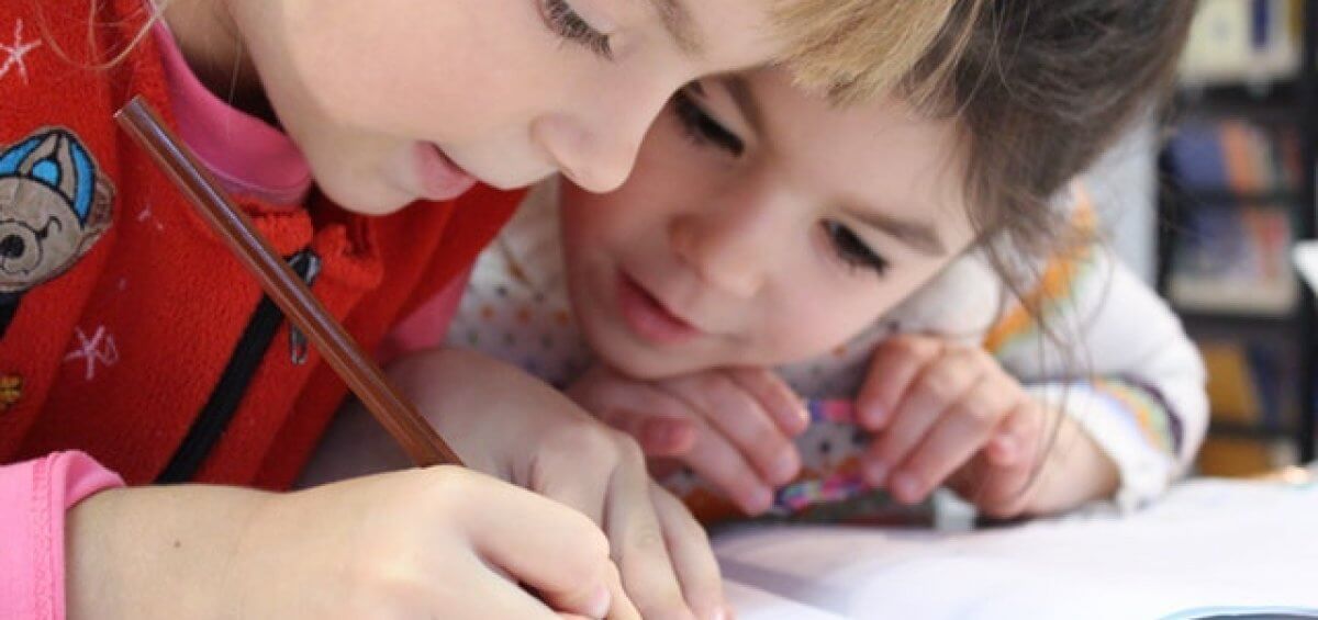 Two young girls doing a pencil drawing at school