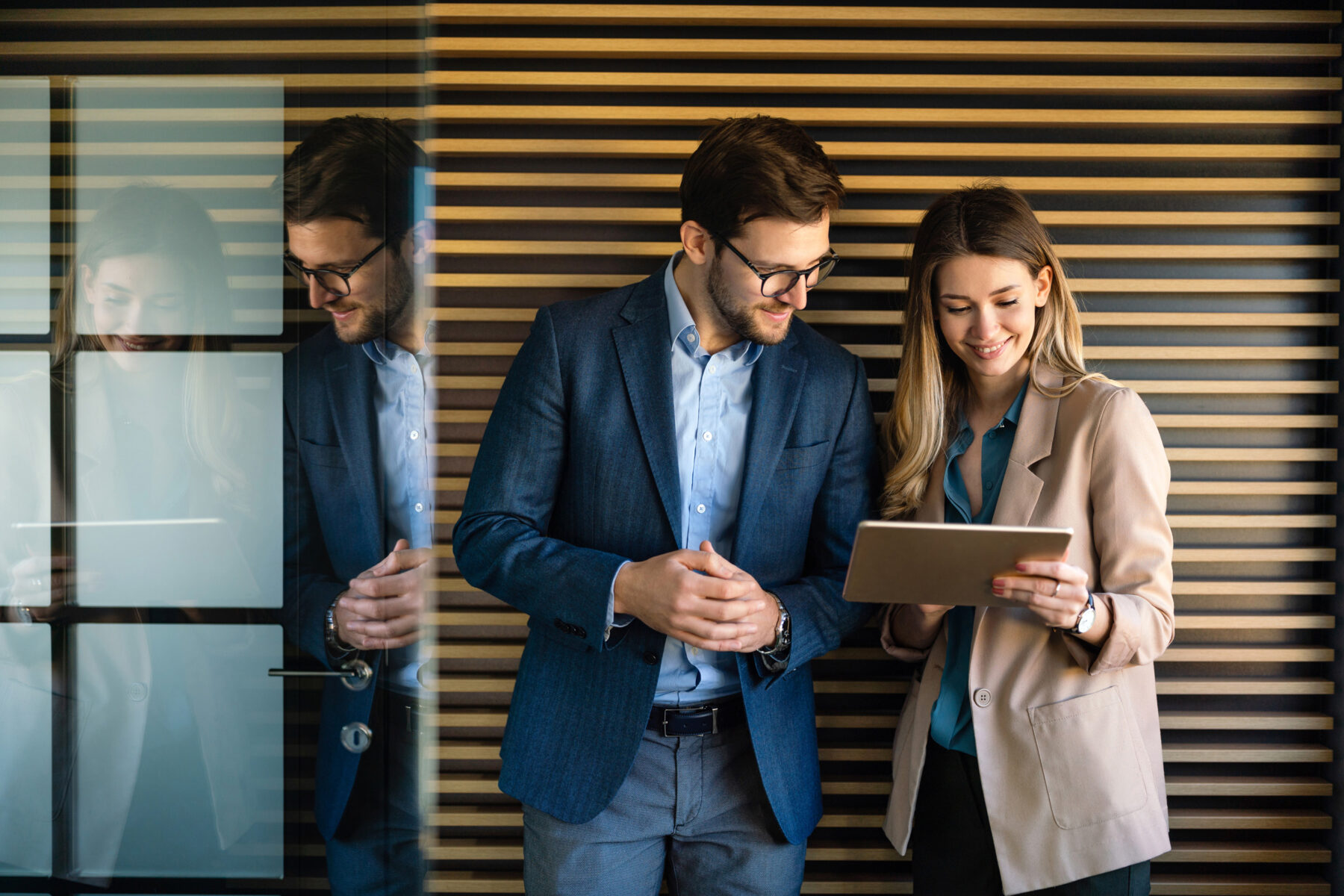Business professionals reviewing information on a tablet in a modern office, representing corporate staffing solutions