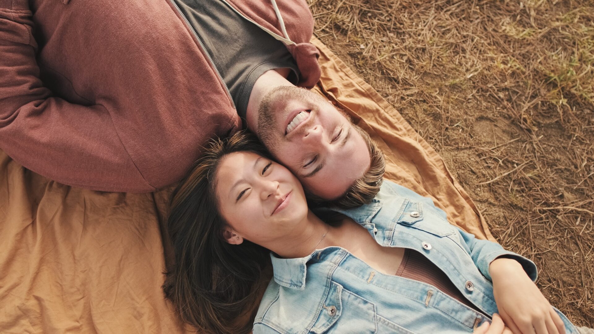 Young couple lying on blanket in the park. View from above