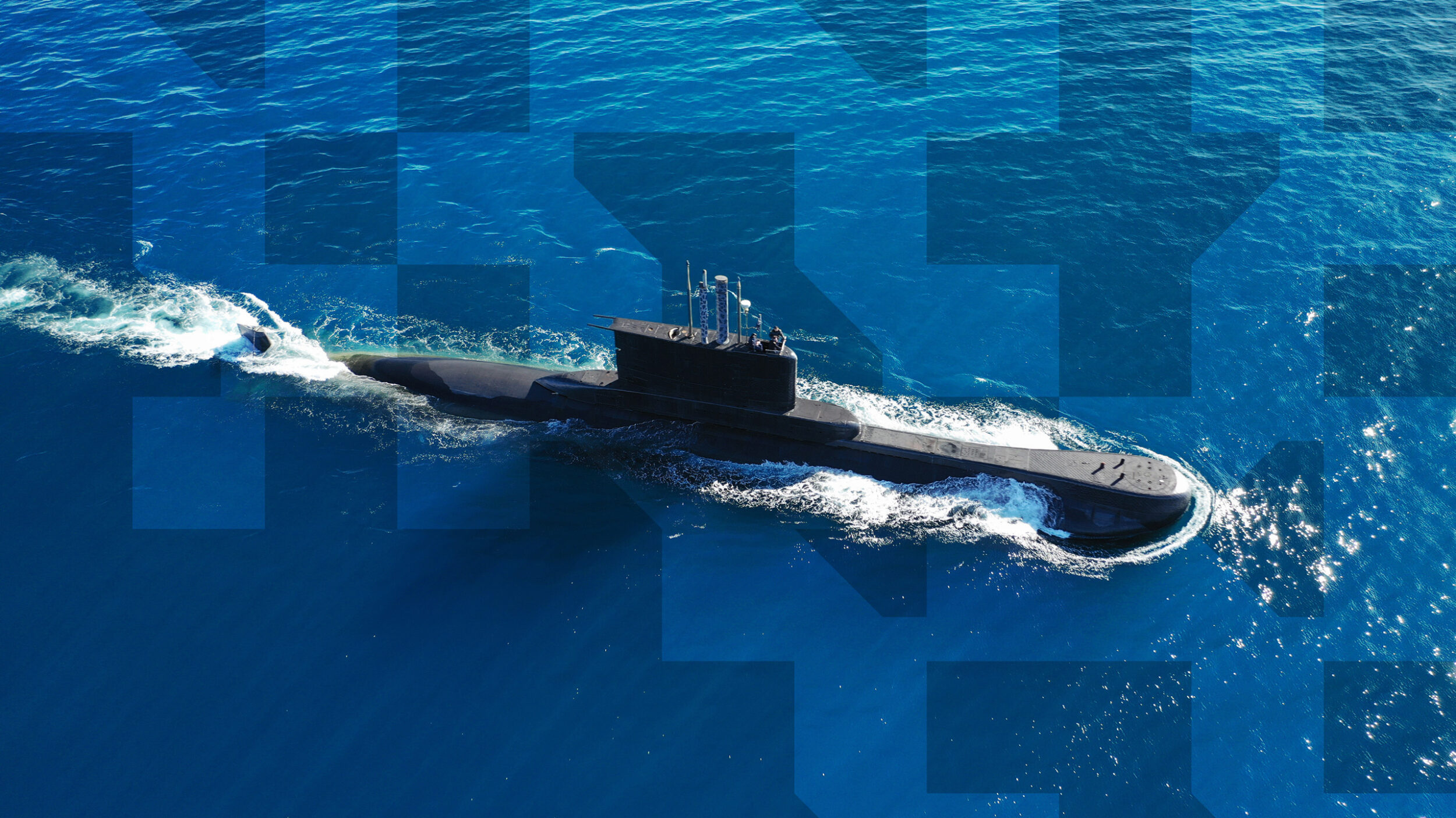 Submarine travelling across open water, viewed from above against a blue ocean surface