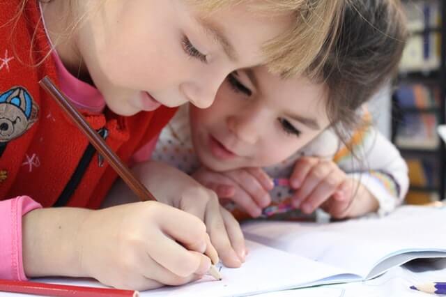 Two young girls doing a pencil drawing at school