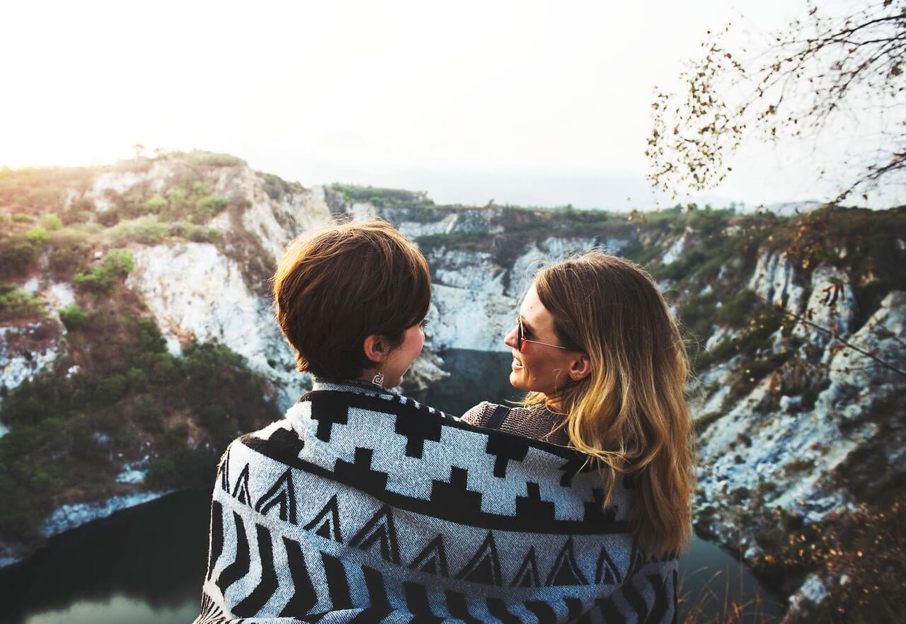 A same sex couple sitting on mountains